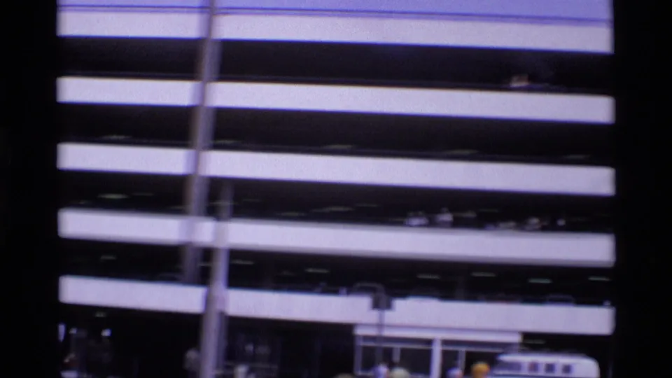 Obstructed 1969 London street view dominated by the parking deck, with a tall lamp, lower entrance area, and cars near the curb.