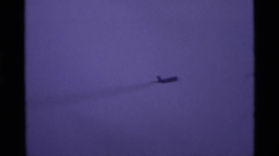 The final frame shows the small aircraft near the lower right of the purple-tinted sky, with grain and soft exposure typical of 8mm home footage.