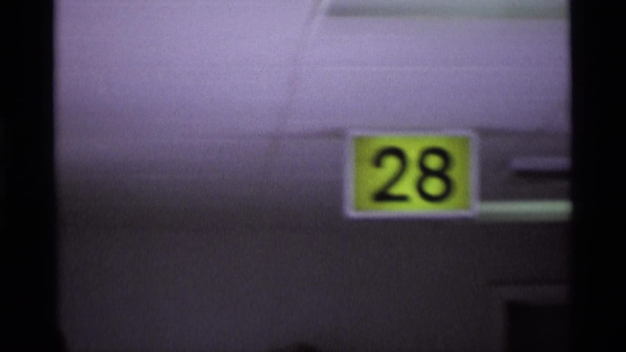 Yellow airport gate sign with the number 28 mounted on a building surface.