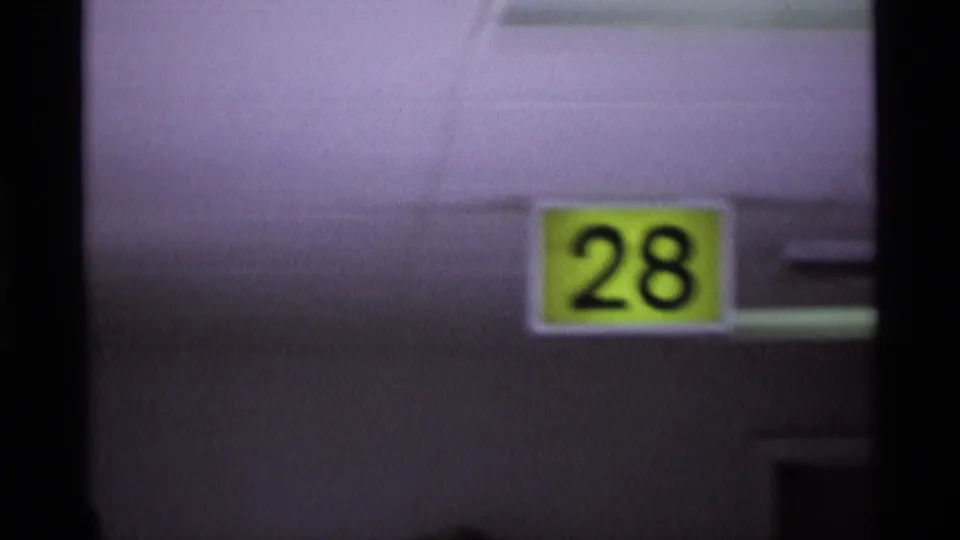 Close view of a yellow Gate 28 sign on an airport building surface, filmed with soft focus and faded color.