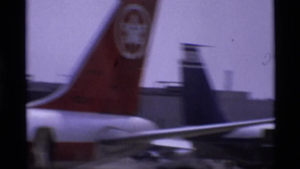 Canadian aircraft tail with a red maple leaf marking at a London airport, with another aircraft tail visible behind it.
