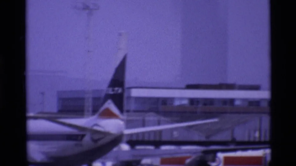 Delta-marked aircraft tail at a London airport in 1969, framed against terminal buildings and apron equipment.