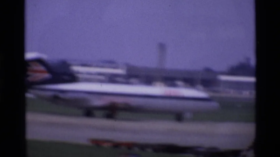 The takeoff view catches another passenger jet on the airfield, softened by speed, focus, and 8mm color shift.
