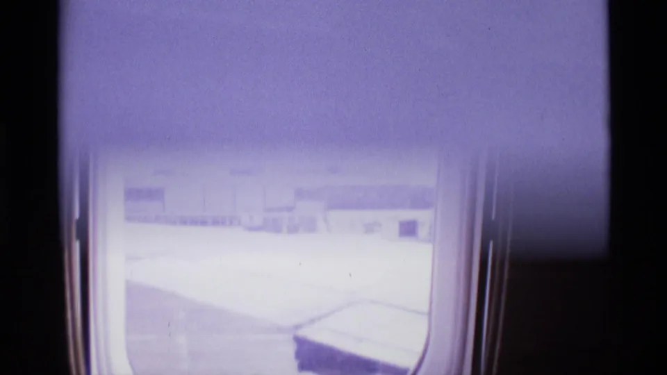 A bright final window view shows airport pavement and faint terminal forms as the 8mm exposure washes out detail.