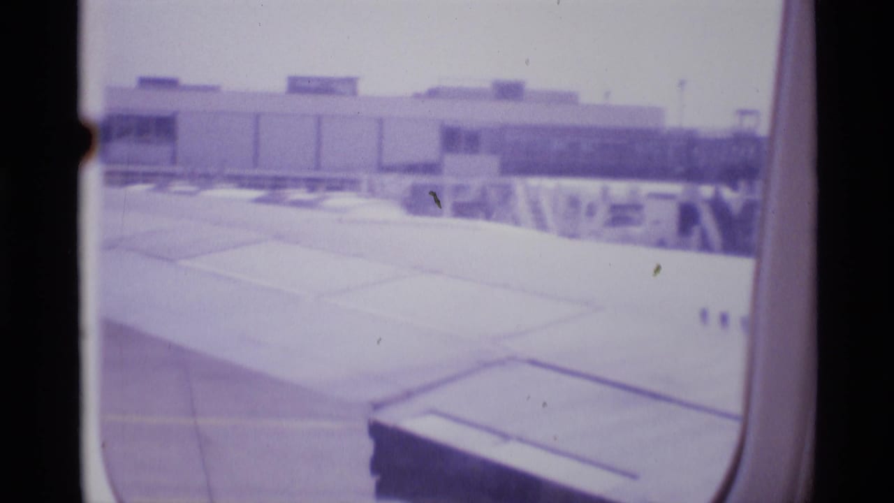 London airport terminal and tarmac viewed from inside a taxiing airplane in 1969 home-movie footage.