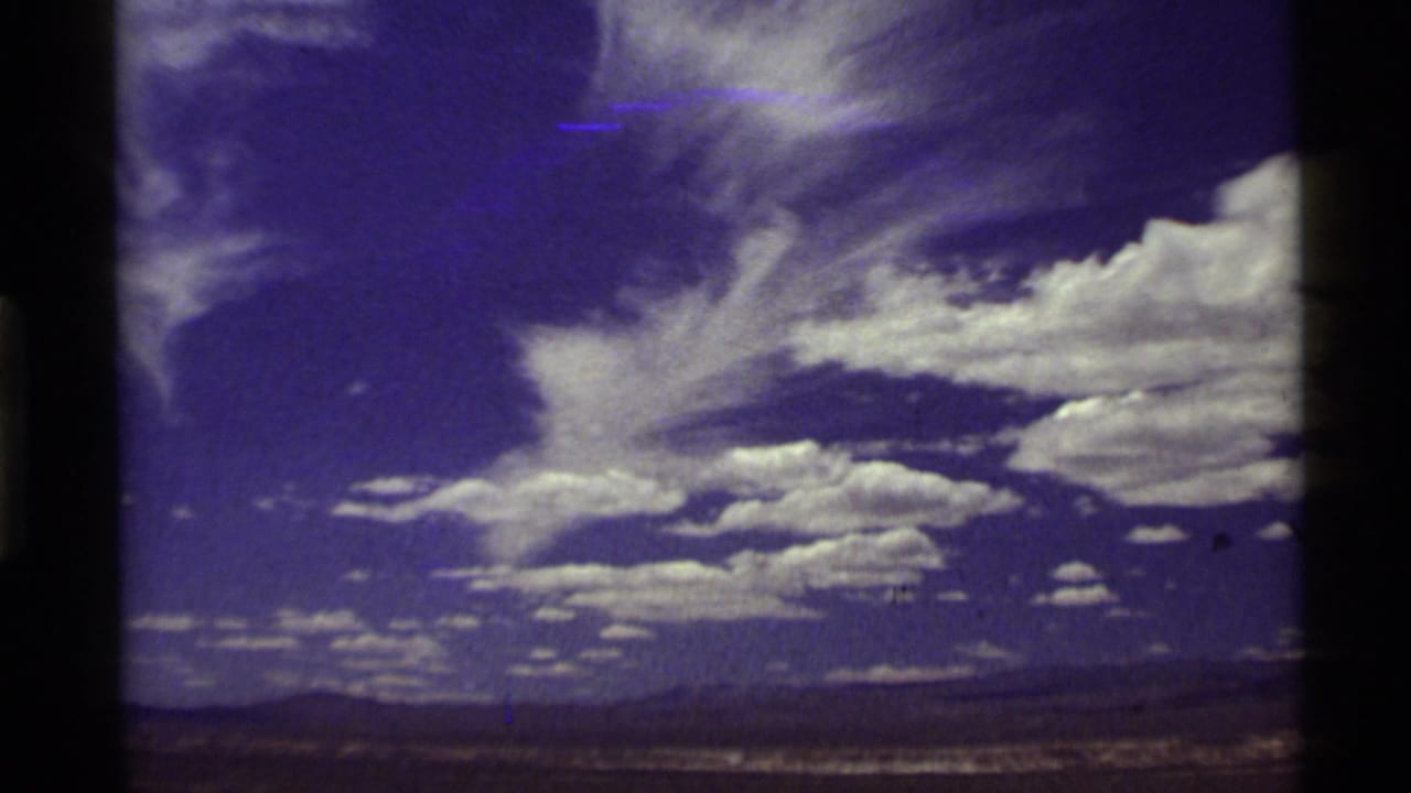 1972 8mm travel footage showing a broad Western sky with white clouds above distant low mountains and open land.
