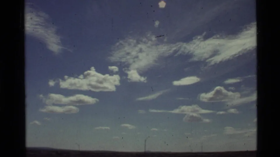 1972 Holland Lake, Montana frame with bright white clouds, wispy high cloud bands, and a low horizon line.