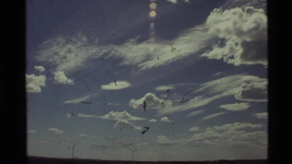 1972 Holland Lake, Montana sky view with small cumulus clouds, streaked high cloud, visible dust marks, and dark 8mm borders.