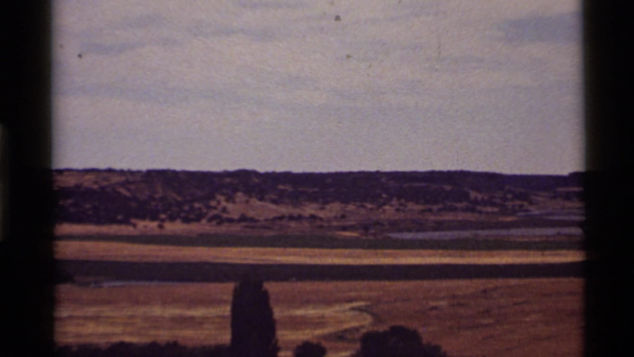 1972 8mm view near Holland Lake, Montana, showing dry plains, distant ridges, pale sky, and visible film gate edges.