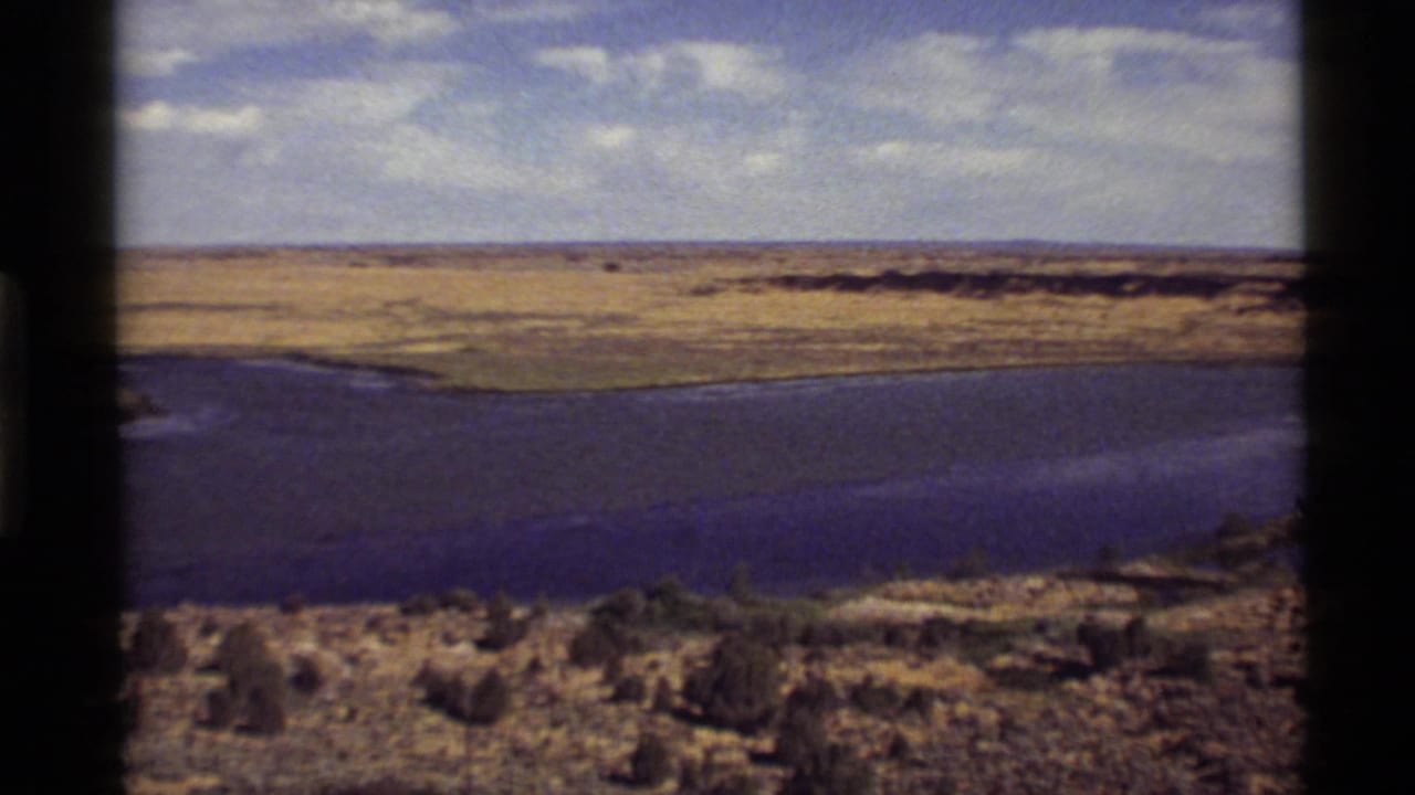 Wide lake view with fields beyond and dark vertical film borders in the frame.