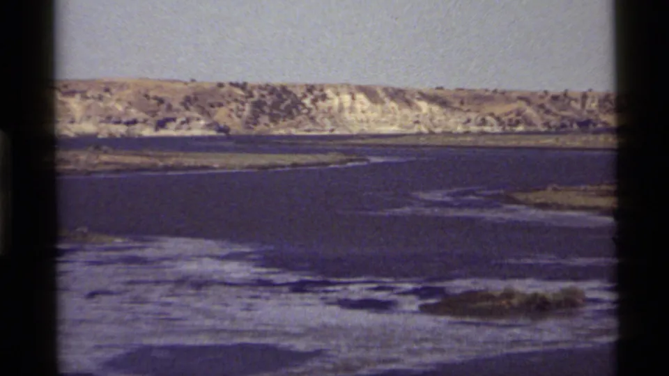 Final 1972 Holland Lake frame with a tighter view of the water, shoreline textures, distant hills, and soft 8mm film color.