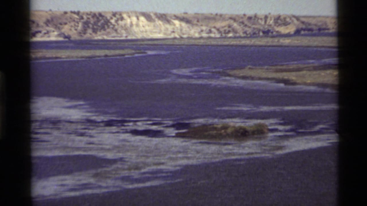 1972 Holland Lake home-movie frame showing a wide view of rippled water and a pale distant shoreline in Montana.