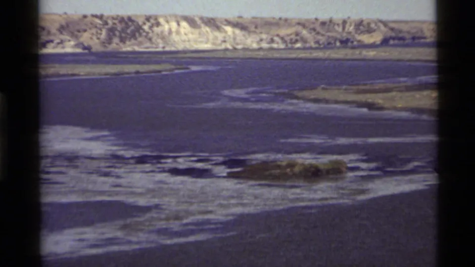 1972 Holland Lake home-movie frame showing a wide view of rippled water and a pale distant shoreline in Montana.