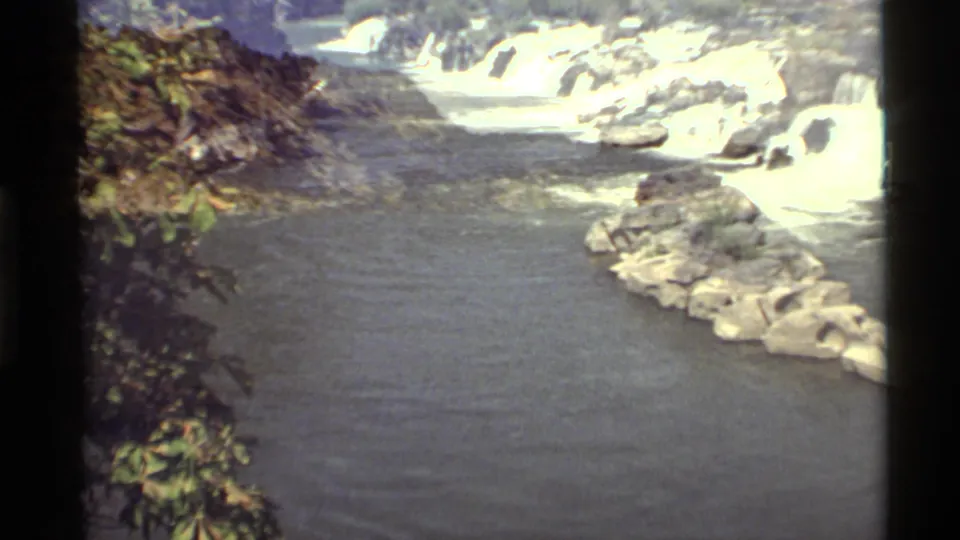 1972 Holland Lake, Montana footage showing water running past rocks and green foliage into a wider pool.