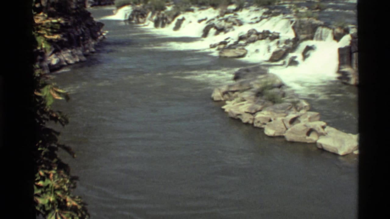 1972 8mm view of rushing water and rocky cascades at Holland Lake, Montana, with foliage along the left edge.