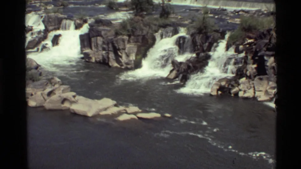 Vintage 8mm frame of Holland Lake, Montana cascades, with rocky shelves and bright white water against a darker river pool.