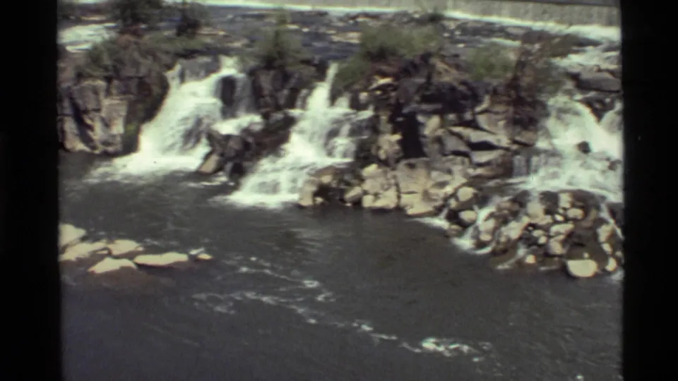 Holland Lake, Montana cascade scene with white water moving over dark rocks and a broad pool in the foreground.