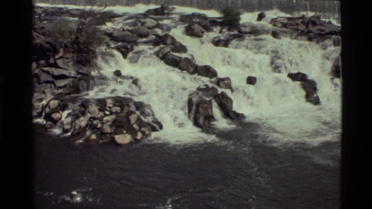 1972 8mm frame of a rocky waterfall at Holland Lake, Montana, with white cascades and dark water below.