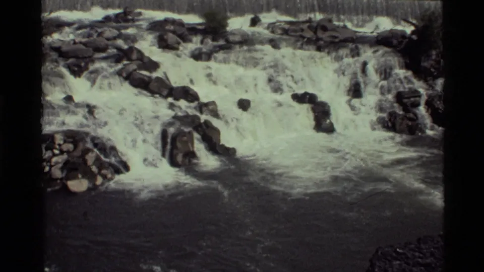 1972 Holland Lake waterfall view on 8mm film, showing frothy water crossing dark rock ledges.