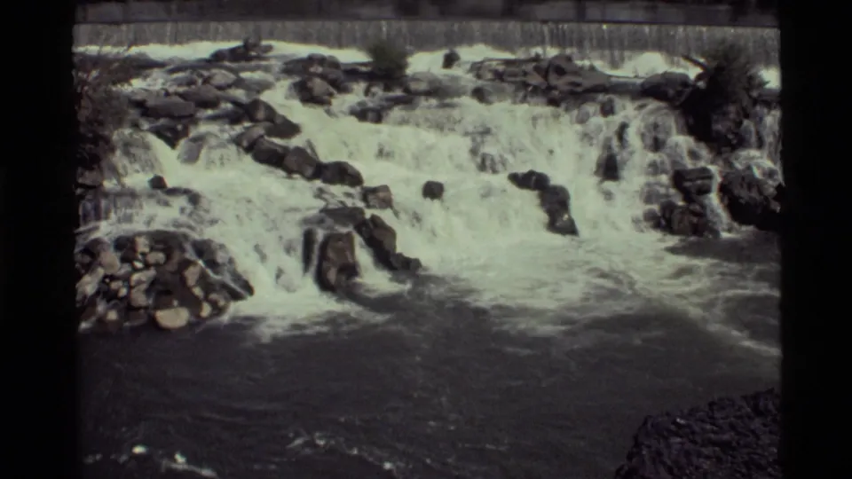1972 8mm view of Holland Lake rushing water, with white froth over rocks and a darker stream foreground.