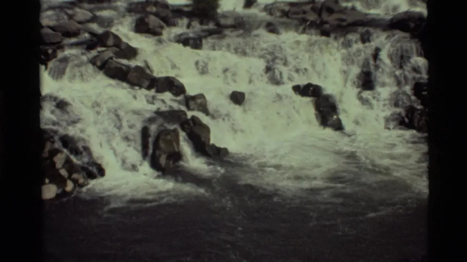 Slightly closer 8mm view of the Holland Lake waterfall, with rushing white water breaking around dark rocks.