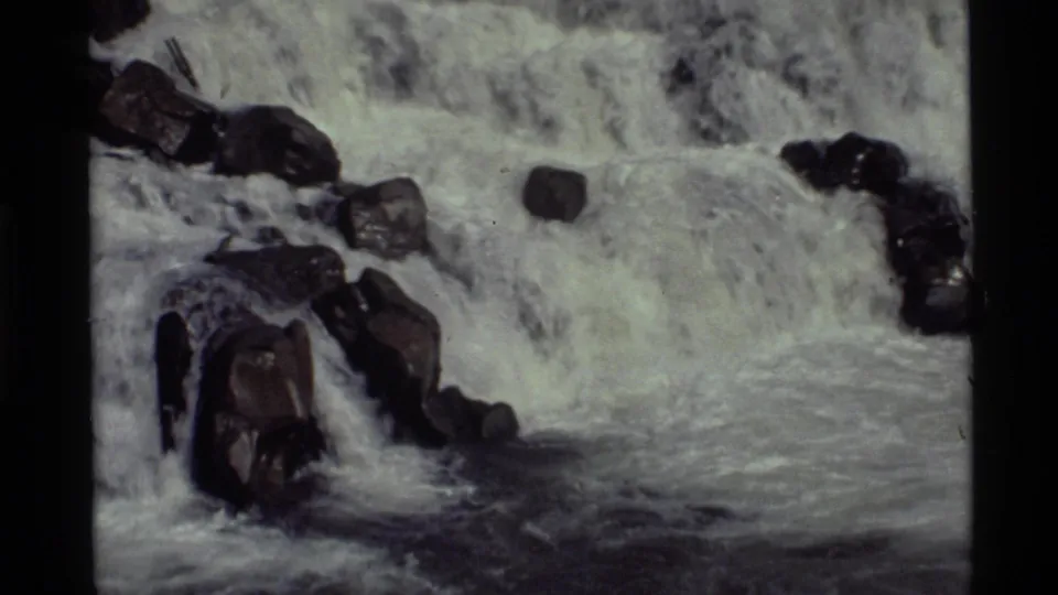 1972 8mm footage at Holland Lake, Montana, showing white water spilling over dark rocks in a small rapid.