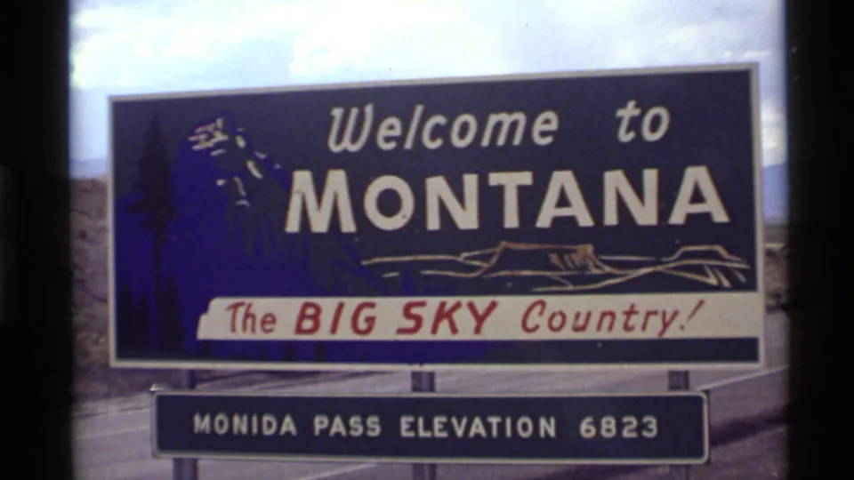 1972 8mm view of the Welcome to Montana sign at Monida Pass, with the Big Sky Country slogan and elevation plaque.