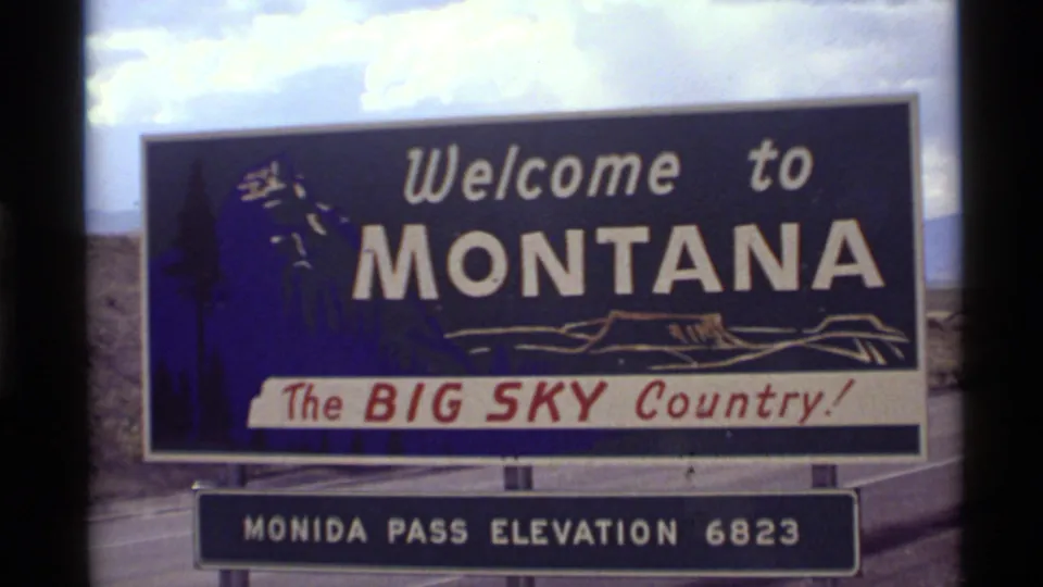 1972 8mm frame showing a closer roadside view of the Welcome to Montana sign and Monida Pass elevation 6823 plaque.