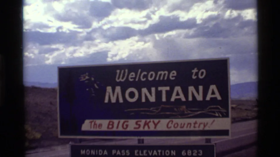 1972 8mm frame of a Montana welcome sign reading Big Sky Country with Monida Pass elevation panel below.