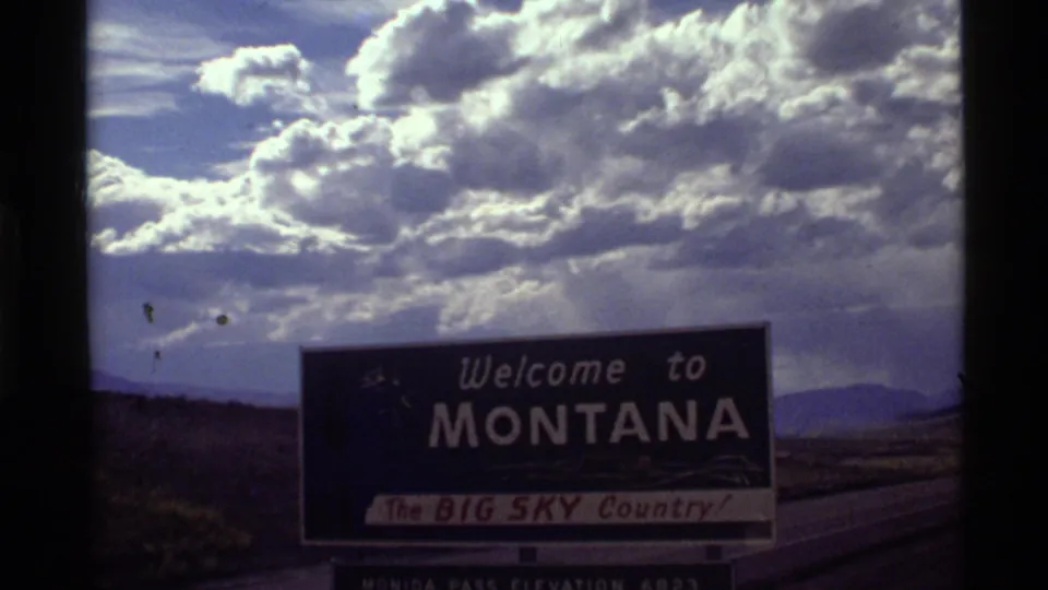 1972 8mm view of the Montana welcome sign and Monida Pass elevation panel below a large Western sky.