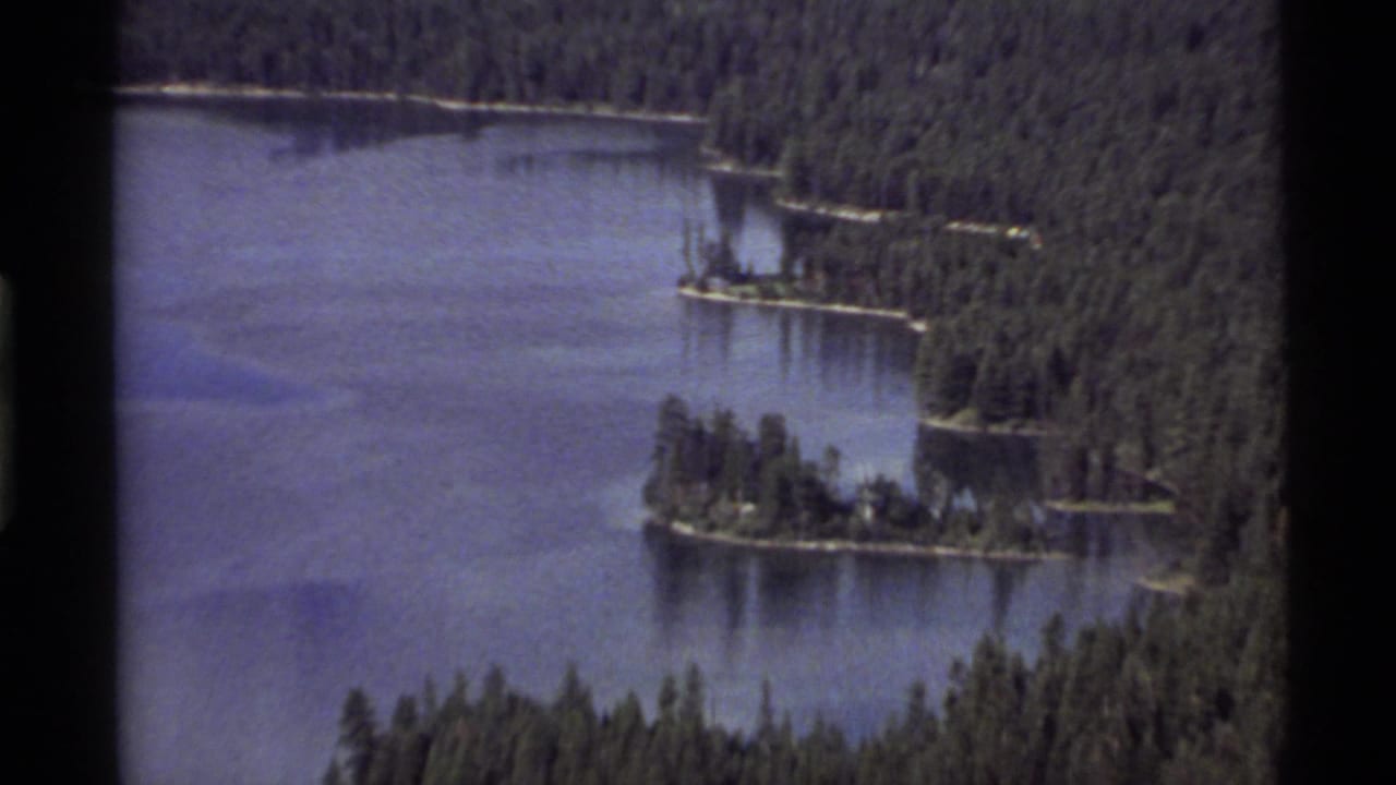 Forested lake with small tree-covered islands and dark film borders.
