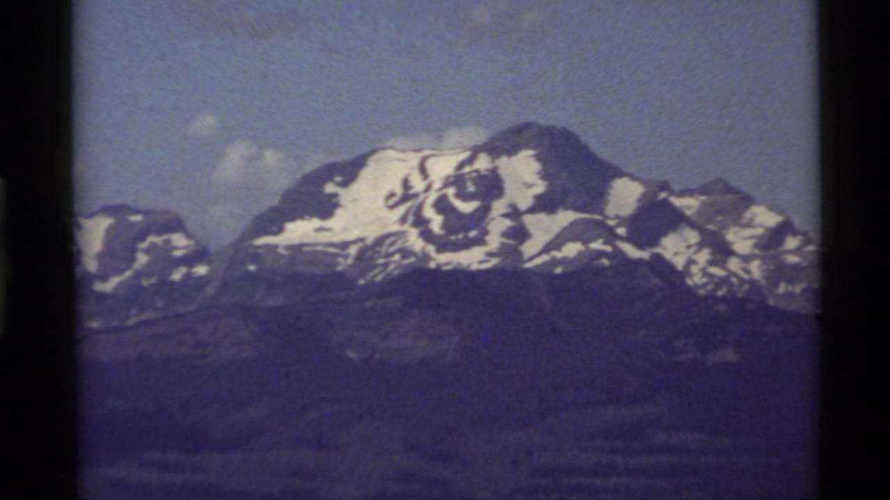 1972 Holland Lake, Montana home-movie view of a distant snowy mountain peak beneath a bright sky.