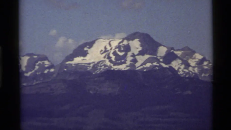 1972 Holland Lake, Montana home-movie view of a distant snowy mountain peak beneath a bright sky.