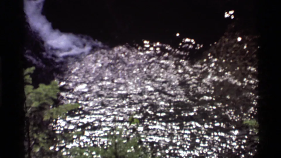 1972 Holland Lake 8mm frame with white falling water above a broad field of sparkling ripples.