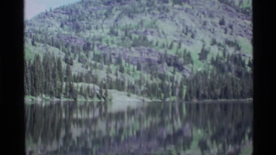 The final frame holds on Holland Lake, where trees and hillside shapes reflect across the calm water.