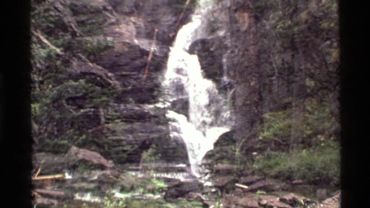 Holland Lake area waterfall in Montana, filmed on 8mm in 1972, with white water crossing layered rock and forest vegetation.
