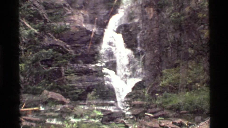 Holland Lake area waterfall in Montana, filmed on 8mm in 1972, with white water crossing layered rock and forest vegetation.