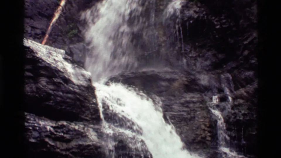 1972 Holland Lake 8mm frame showing the lower waterfall flow crossing wet rock shelves and small side trickles.