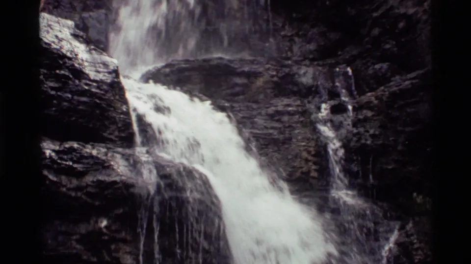 Vintage 8mm frame from Holland Lake, Montana, showing white water flowing diagonally through a rugged rock channel.
