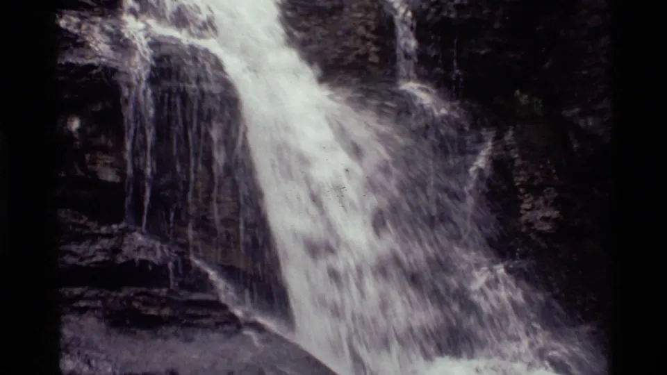 Black-and-white 8mm view of a waterfall spilling down a rugged Holland Lake rock formation.
