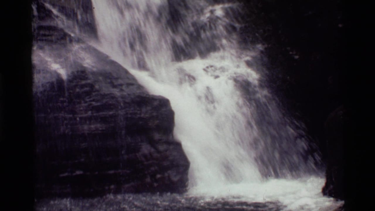 1972 8mm frame from Holland Lake, Montana, showing white water cascading over dark layered rock.