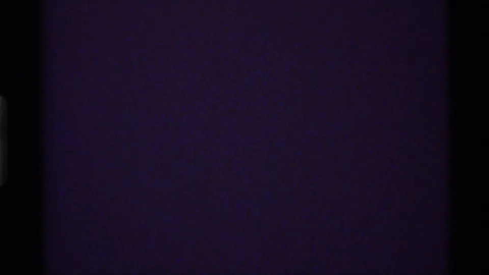 Dark transitional 8mm frame from the Holland Lake clip with minimal visible detail and strong film color cast.