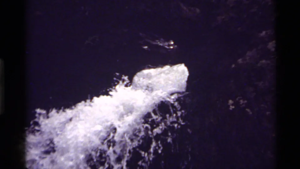 Close 1972 8mm view of foaming water rushing over dark rock at Holland Lake, Montana.