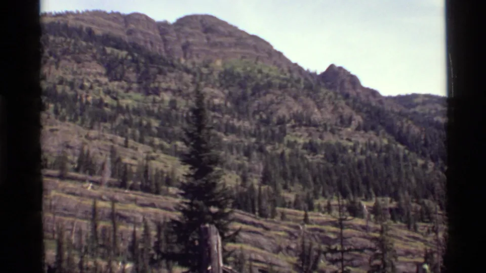 The home-movie view remains on the Holland Lake mountain slope, with forest patches and rocky terrain visible.