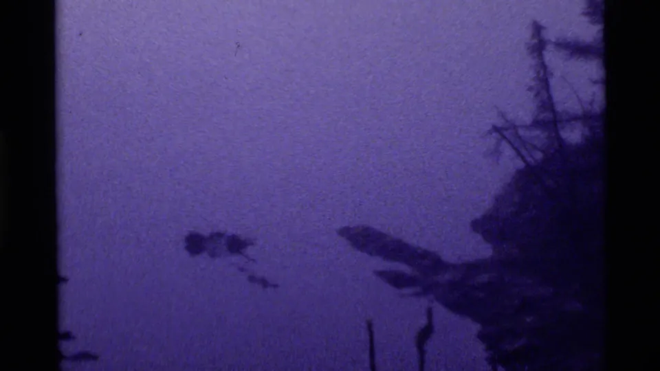 1972 Holland Lake frame with still purple water, silhouetted lakeshore trees, and a small dark shape floating across the lake surface.