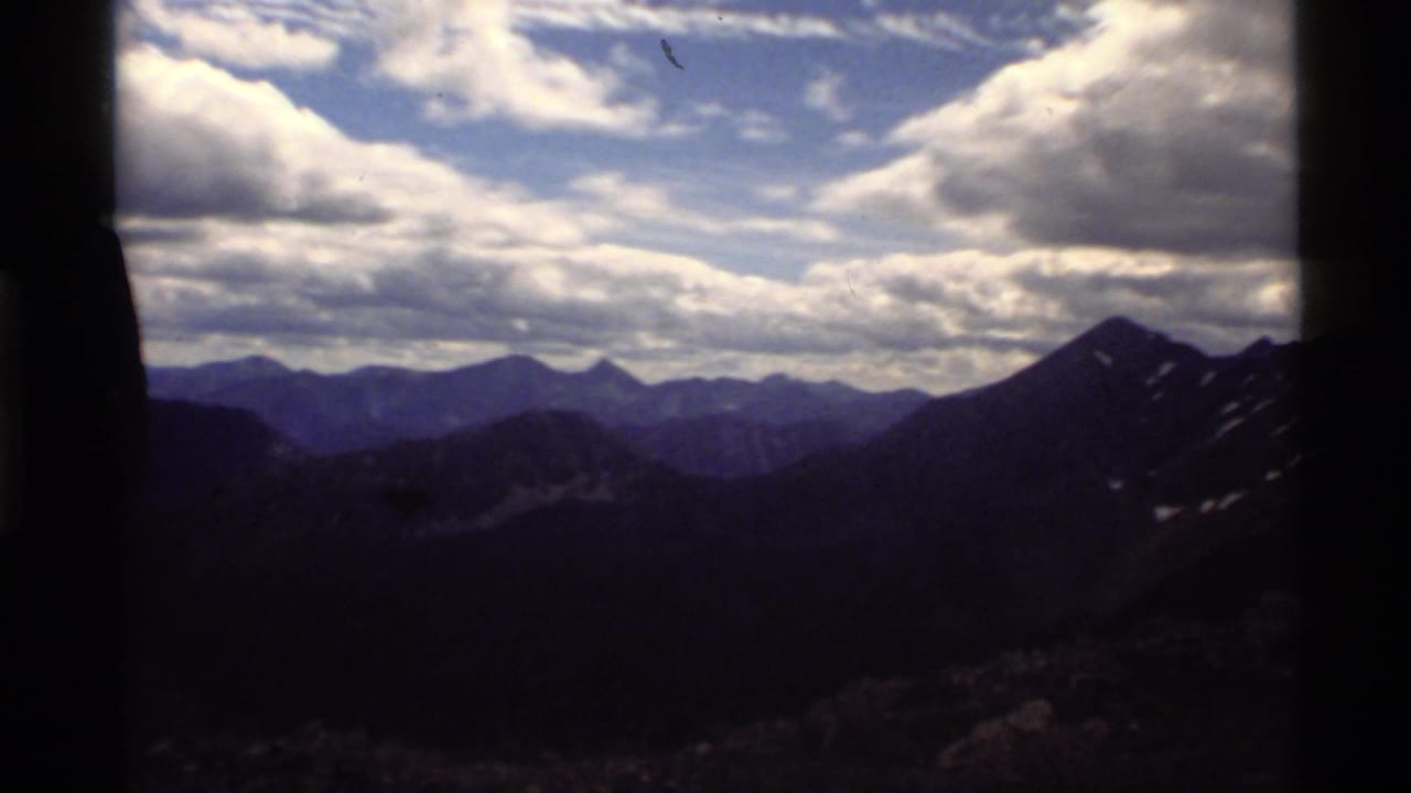 Mountain ridges under a cloud-filled sky with dark film borders at the sides.