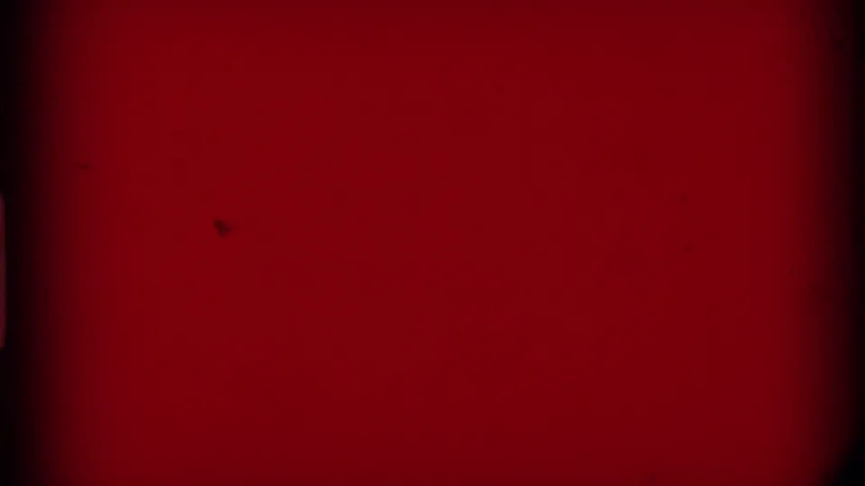 Red leader or exposed end frame from the 8mm home movie, with dark edge marks visible.