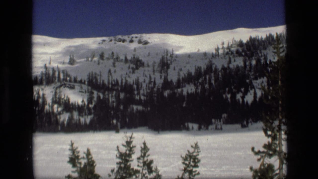A 1972 Idaho winter landscape shows a snowy hillside, scattered evergreens and an open white field in the foreground.
