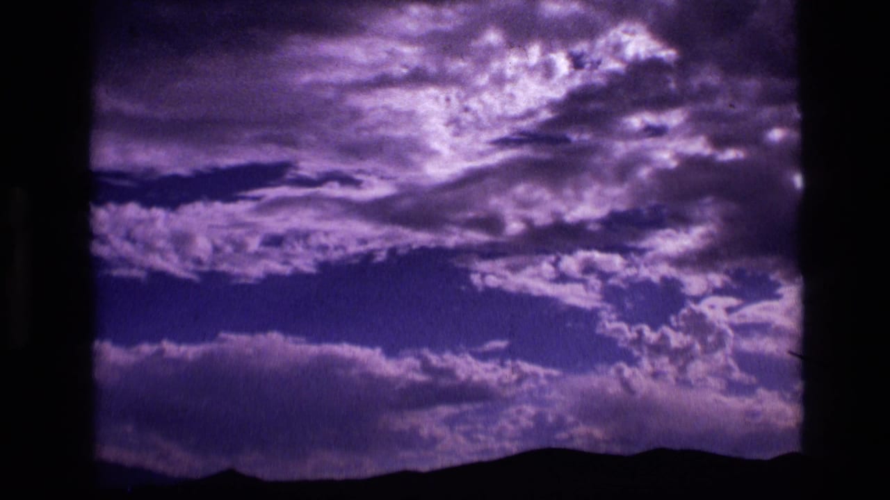 1972 Idaho 8mm frame showing violet cloud cover above a silhouetted mountain horizon.