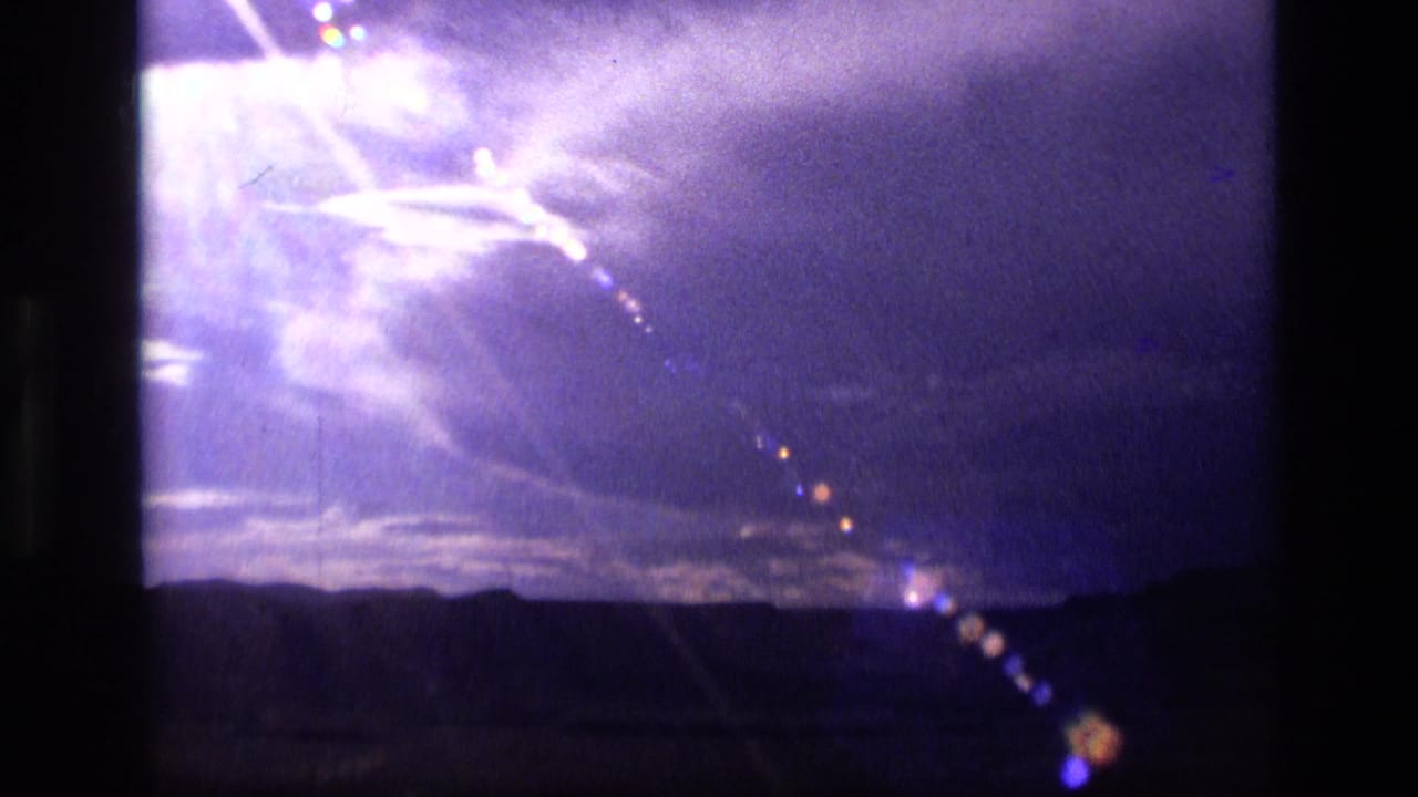 Purple-blue sky over a dark ridgeline with bright glare and lens flare.